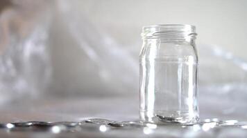 Glass jar with scattered coins on a surface video
