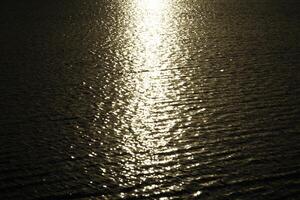 Sun reflecting in water surface at sunset photo