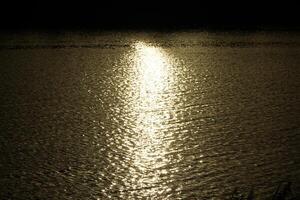 Sun reflecting in water on sunset photo