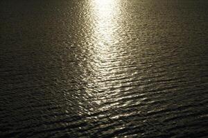 Sun reflecting in water surface at sunset photo