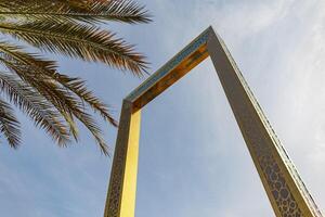 Beautiful golden building frame in Dubai, UAE with palm tree photo