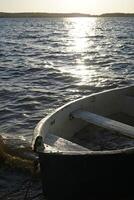 Old boat on lake shore at sunset photo