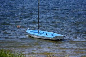 Blue yacht without sails at lake shore photo