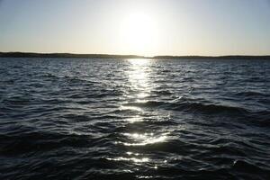 Sun reflecting in lake water surface photo