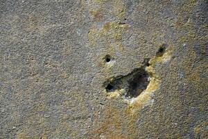 Rough old concrete wall texture with bullet wholes and scratches photo