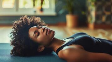 A person lying on a yoga mat their eyes closed and body relaxed as they take part in a mindful body scan exercise photo