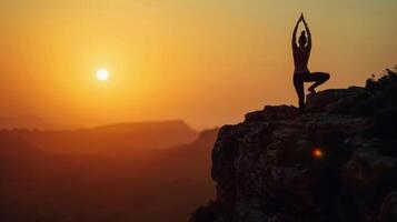 A silhouetted figure of a person practicing yoga poses on a cliff during sunset highlighting the brainboosting benefits of a regular yoga practice photo