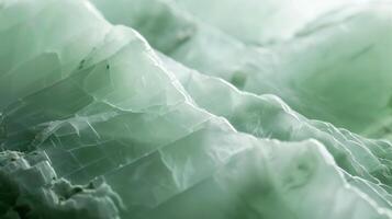 The surface of a smooth jade gemstone appears almost luminescent reflecting a pale green light that masks any visible texture photo