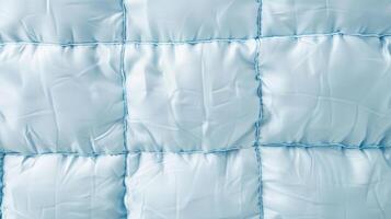 A zoomedin image of a quilted insulation material with rows of square pockets featuring a soft padded texture in a pale blue hue photo