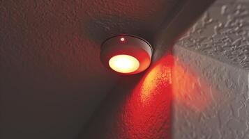A smoke detector with a bright red light flashing signaling a potential fire hazard photo
