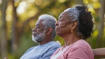 A senior couple sitting on a bench in the park practicing a mindful breathing exercise and enjoying the present moment together photo