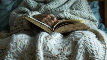 An elderly person snuggled up in a cozy bed with a book emphasizing the role of a relaxing bedtime routine in promoting healthy sleep photo