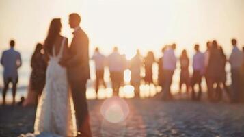 A hazy view of a beach wedding with the bride and groom standing at the center of the blurred guests and scenery photo