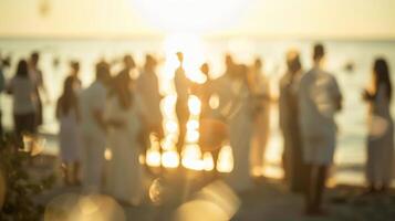 Blurred outlines of guests dressed in white standing on the shore for an intimate beach wedding photo