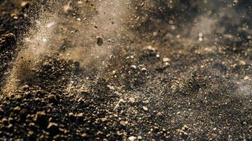 A closeup of dusty dirt with fine particles seen in the air and a powdery texture visible on the surface photo