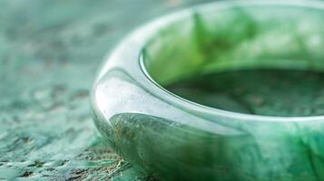 A macro shot of a delicately smooth shimmering jade bangle with a milky green hue highlighting its glossy finish photo
