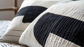 The closeup of a modern quilted throw pillow showcases a dynamic mix of bold abstract shapes and graphic lines in black and white photo