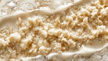 Detailed view of lumpy oatmeal with a thick layer of cream on top highlighting the contrast between the smooth and bumpy textures photo