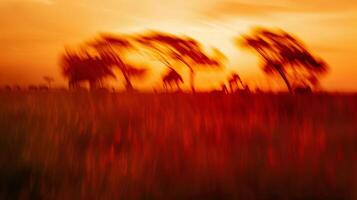 A blur of animals their distinct shapes ly visible against a backdrop of brilliant oranges and deep reds in the savanna sunset. photo