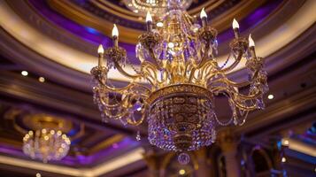 Soft hues of purple and gold blur together in the background as all attention is drawn to the cascading crystals of the grand chandelier illuminating the lavish surroundings of the photo