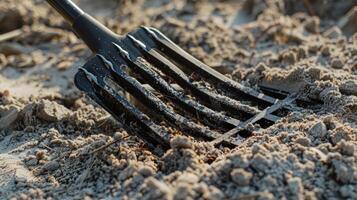 A collapsible rake with wide teeth for sifting through sand and debris photo