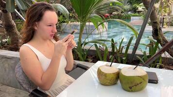 Drinking coconut in a tropical country on vacation girl is broadcasting live, filming a block for social networks, and posting a . video