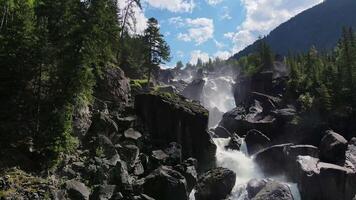 Aerial view of the cascading Uchar waterfall, flowing over rocks and forests video
