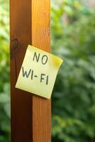 Paper note with text NO WI FI in wooden greenery garden background. Concept of digital detox, unplugging from technology break. Mindful living without gadgets photo
