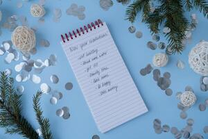 New year's resolutions on paper note with Christmas decor. Making promises for new year, setting goals. Creating dream vision board motivation photo