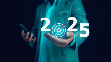 Businessman holds text 2025 with arrow target, Implementation of business goals plan, Set goals for 2025, Development to achieve goals and success. photo