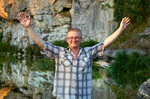 Cheerful smiling man tourist stands on a mountain river canyon photo