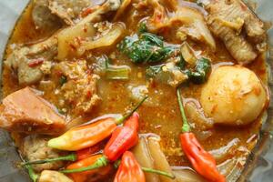 Seblak is a Indonesian dish with a savory and spicy taste. Made from wet crackers cooked with vegetables, sausage, eggs, chicken feet, seafood and processed beef. a bowl of seblak on a wooden table. photo