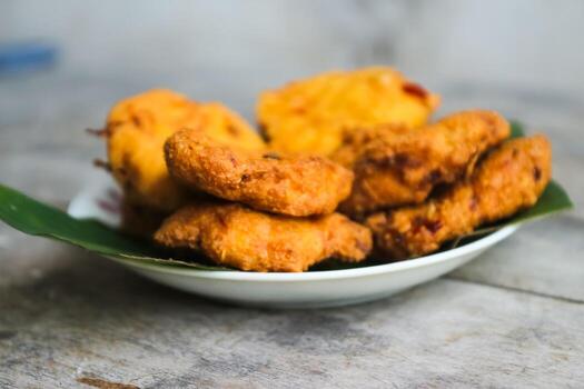un pila de tofu buñuelos o frito tofu un pan en un hoja lámina. hecho desde un mezcla machacado tofu, un pequeño tapioca harina, verde cebollas, huevos, sal y pimienta. crujiente en el afuera, suave en el dentro foto