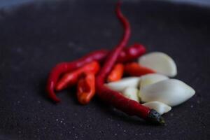 a pile of chilies and onions on a stone mortar and pestle to grind the ingredients for making traditional chili sauce. Traditional Indonesian sambal or chili sauce. photo
