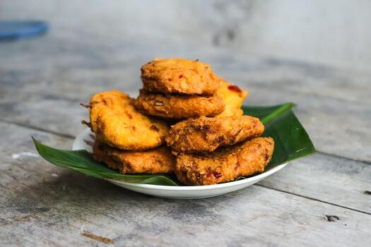 un pila de tofu buñuelos o frito tofu un pan en un hoja lámina. hecho desde un mezcla machacado tofu, un pequeño tapioca harina, verde cebollas, huevos, sal y pimienta. crujiente en el afuera, suave en el dentro foto