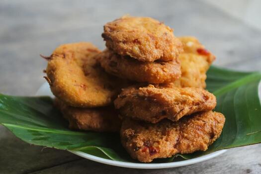 un pila de tofu buñuelos o frito tofu un pan en un hoja lámina. hecho desde un mezcla machacado tofu, un pequeño tapioca harina, verde cebollas, huevos, sal y pimienta. crujiente en el afuera, suave en el dentro foto