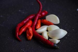 a pile of chilies and onions on a stone mortar and pestle to grind the ingredients for making traditional chili sauce. Traditional Indonesian sambal or chili sauce. photo