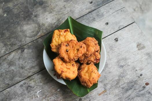 un pila de tofu buñuelos o frito tofu un pan en un hoja lámina. hecho desde un mezcla, machacado tofu, un pequeño tapioca harina, verde cebollas, huevos, sal y pimienta. crujiente en el afuera, suave en el dentro foto