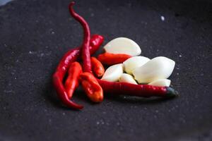 a pile of chilies and onions on a stone mortar and pestle to grind the ingredients for making traditional chili sauce. Traditional Indonesian sambal or chili sauce. photo