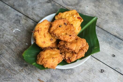 un pila de tofu buñuelos o frito tofu un pan en un hoja lámina. hecho desde un mezcla, machacado tofu, un pequeño tapioca harina, verde cebollas, huevos, sal y pimienta. crujiente en el afuera, suave en el dentro foto