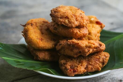 un pila de tofu buñuelos o frito tofu un pan en un hoja lámina. hecho desde un mezcla machacado tofu, un pequeño tapioca harina, verde cebollas, huevos, sal y pimienta. crujiente en el afuera, suave en el dentro foto