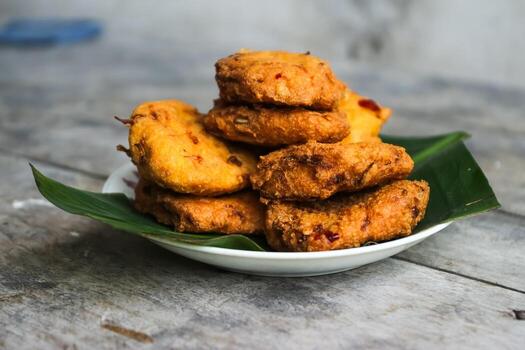 un pila de tofu buñuelos o frito tofu un pan en un hoja lámina. hecho desde un mezcla machacado tofu, un pequeño tapioca harina, verde cebollas, huevos, sal y pimienta. crujiente en el afuera, suave en el dentro foto