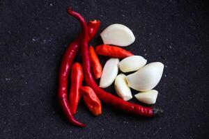 a pile of chilies and onions on a stone mortar and pestle to grind the ingredients for making traditional chili sauce. Traditional Indonesian sambal or chili sauce. photo