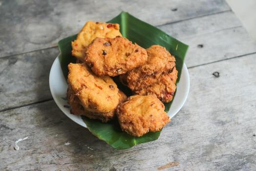 un pila de tofu buñuelos o frito tofu un pan en un hoja lámina. hecho desde un mezcla machacado tofu, un pequeño tapioca harina, verde cebollas, huevos, sal y pimienta. crujiente en el afuera, suave en el dentro foto