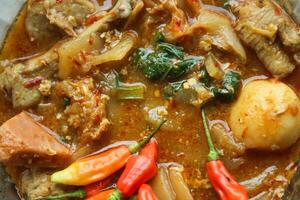 Seblak is a Indonesian dish with a savory and spicy taste. Made from wet crackers cooked with vegetables, sausage, eggs, chicken feet, seafood and processed beef. a bowl of seblak on a wooden table. photo