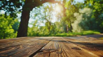 Empty old wooden table in front of blurred background of the big tree, grass in the park with blue sky among bright sunlight on a clear day photo