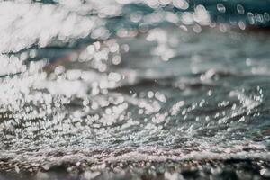 Blurred golden sea at sunset. The sun reflects and sparkles on the waves with bokeh, illuminating the golden sea. Holiday recreation concept. Abstract nautical summer ocean sunset nature background. photo