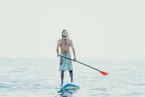 Man Sup Sea. Strong athletic man learns to paddle sup standing on board in open sea ocean on sunny day. Summer holiday vacation and travel concept. Aerial view. Slow motion photo