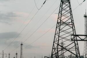 High voltage electric distribution network at sunset. Power transmission lines on supports with ceramic insulators and transformers at large electrical distribution substation photo