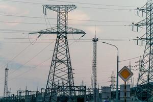 High voltage electric distribution network at sunset. Power transmission lines on supports with ceramic insulators and transformers at large electrical distribution substation photo
